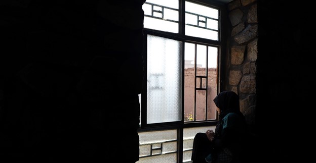 Una mujer sentada junto a la ventana en Afganistán