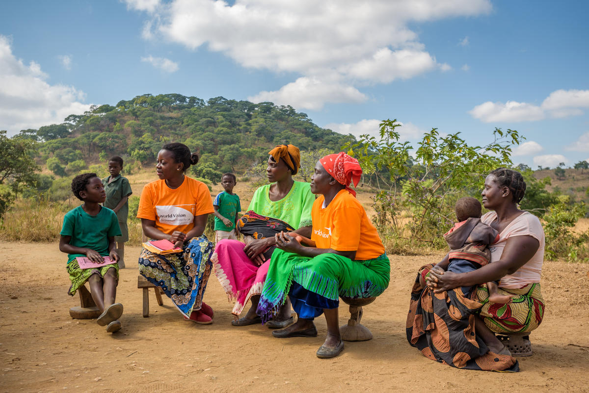 Odness Mudenda, una niña aadrinada de 9 años,  habla con Agatha Mali, miembro del personal de World Vision Zambia, y con otros miembros de la comunidad