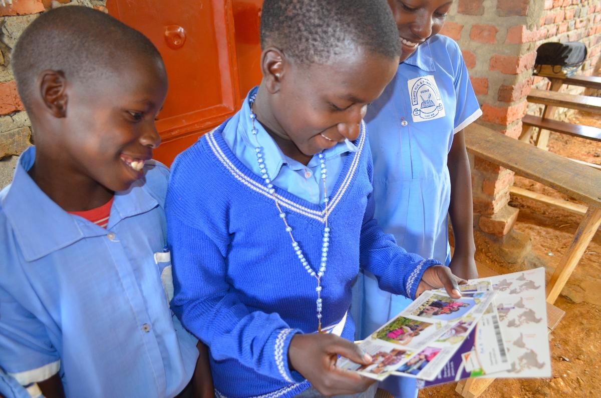 Kasonga, un niño apadrinado de Uganda, le enseña a sus amigos las cartas que ha recibido de su padrino 