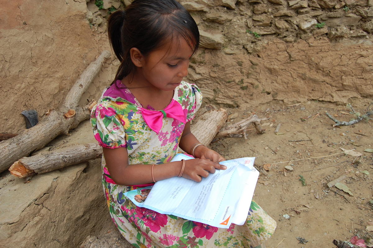 Sharu, una niña apadrinada de 9 años vive en un pueblo remoto de Nepal, disfruta leyendo la carta escrita por su padrino