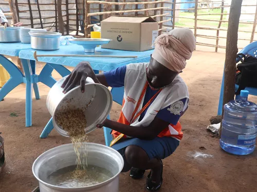 Flora Mandera, miembro del personal de nutrición de World Vision, demostrando a las madres la mejor manera de cocinar el VitaMeal en sus hogares.