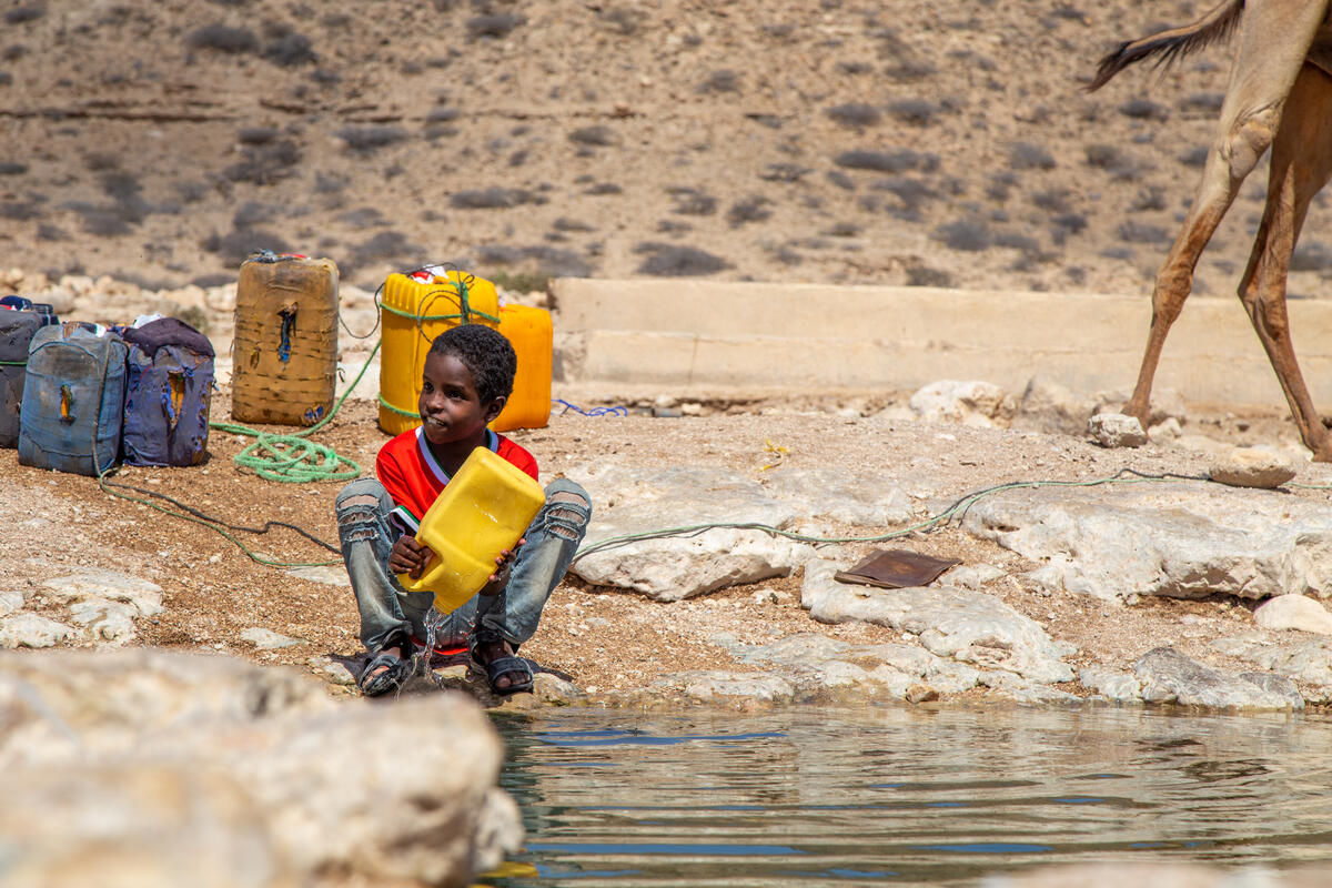 Niño de Somalia llenando tinas de agua en el lago