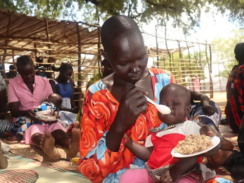 Yar Achien, de 35 años, alimentando a su hijo Dio Jok, de 11 meses, con los VitaMeal preparados en el centro.