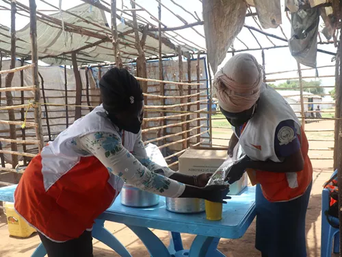 Dos empleados de World Vision empaquetan VitaMeal, compuesto por lentejas, arroz, vitaminas y minerales.