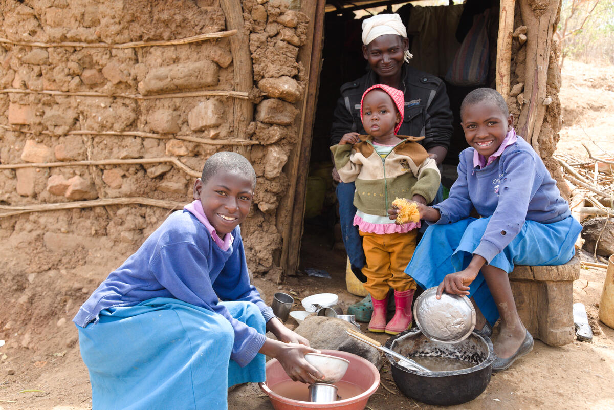 Anastacia, de Kenia, y sus hijas lavan los platos después de comer una pequeña ración de maíz.