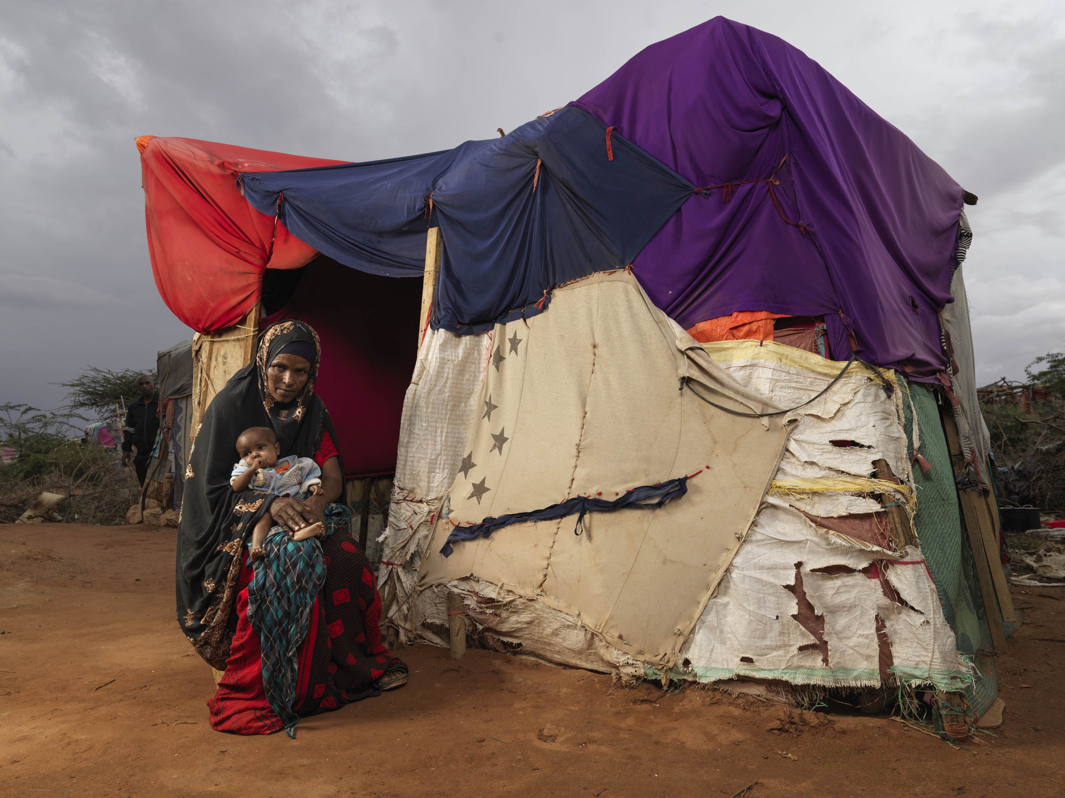 Mujer somalí con un bebé delante de un refugio improvisado.