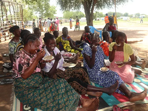 Mary Michael, de 33 años, madre de siete hijos, y otras madres, disfrutan de la comida y agradecen a World Vision su formación para prevenir la desnutrición.