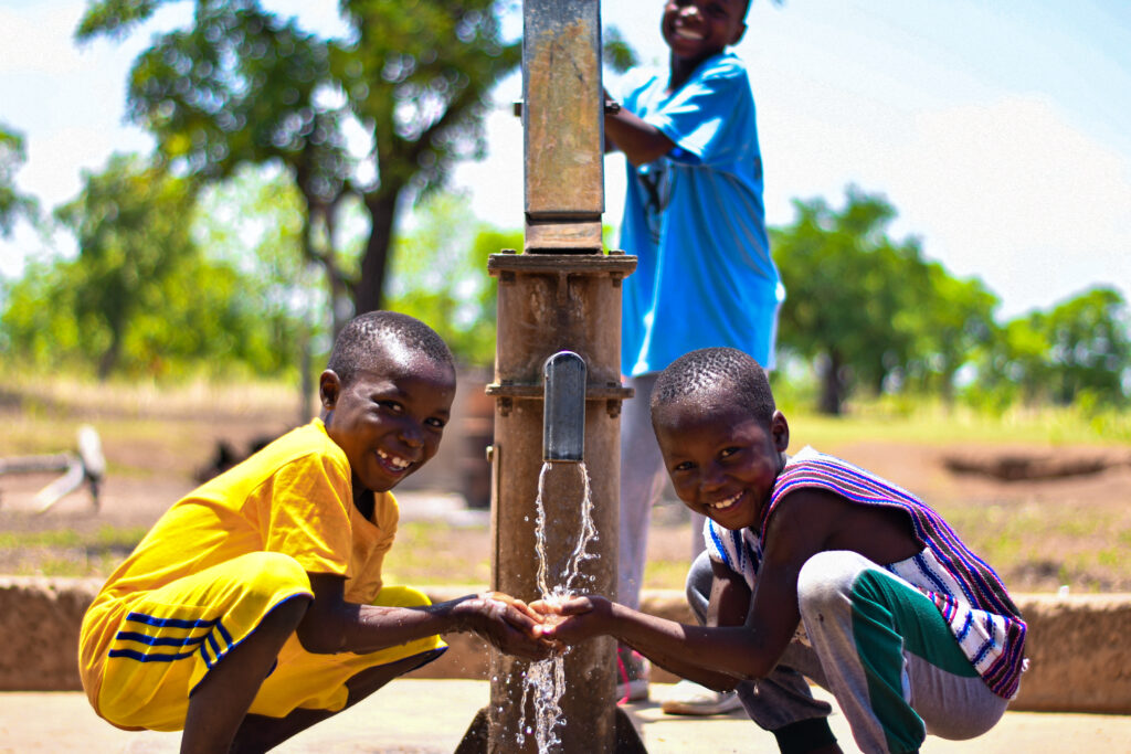 Happy children accessing water from a World Vision-drilled borehole in Zabzugu.